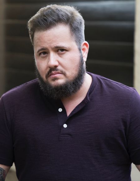 Chaz Bono in a black t-shirt poses for a picture.